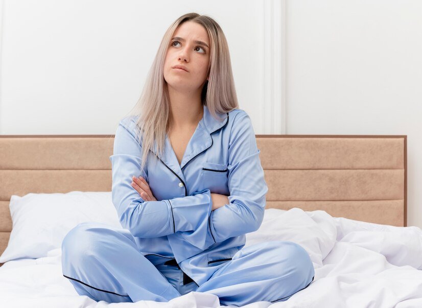 offended young beautiful woman blue pajamas sitting bed looking up with hands crossed chest bedroom interior light background 141793 46006